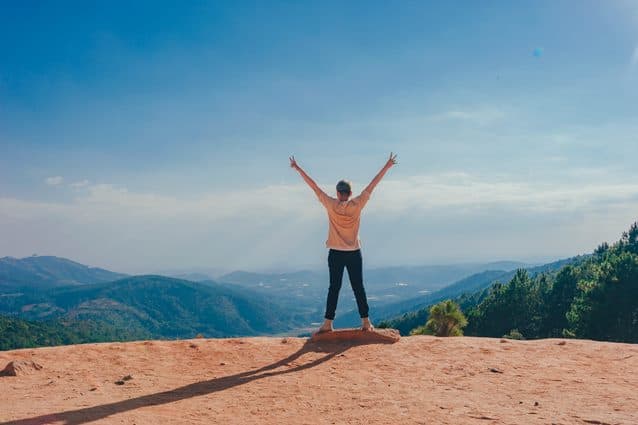 Woman standing on a cliff top looking triumphant to signify the end of the financial myths article