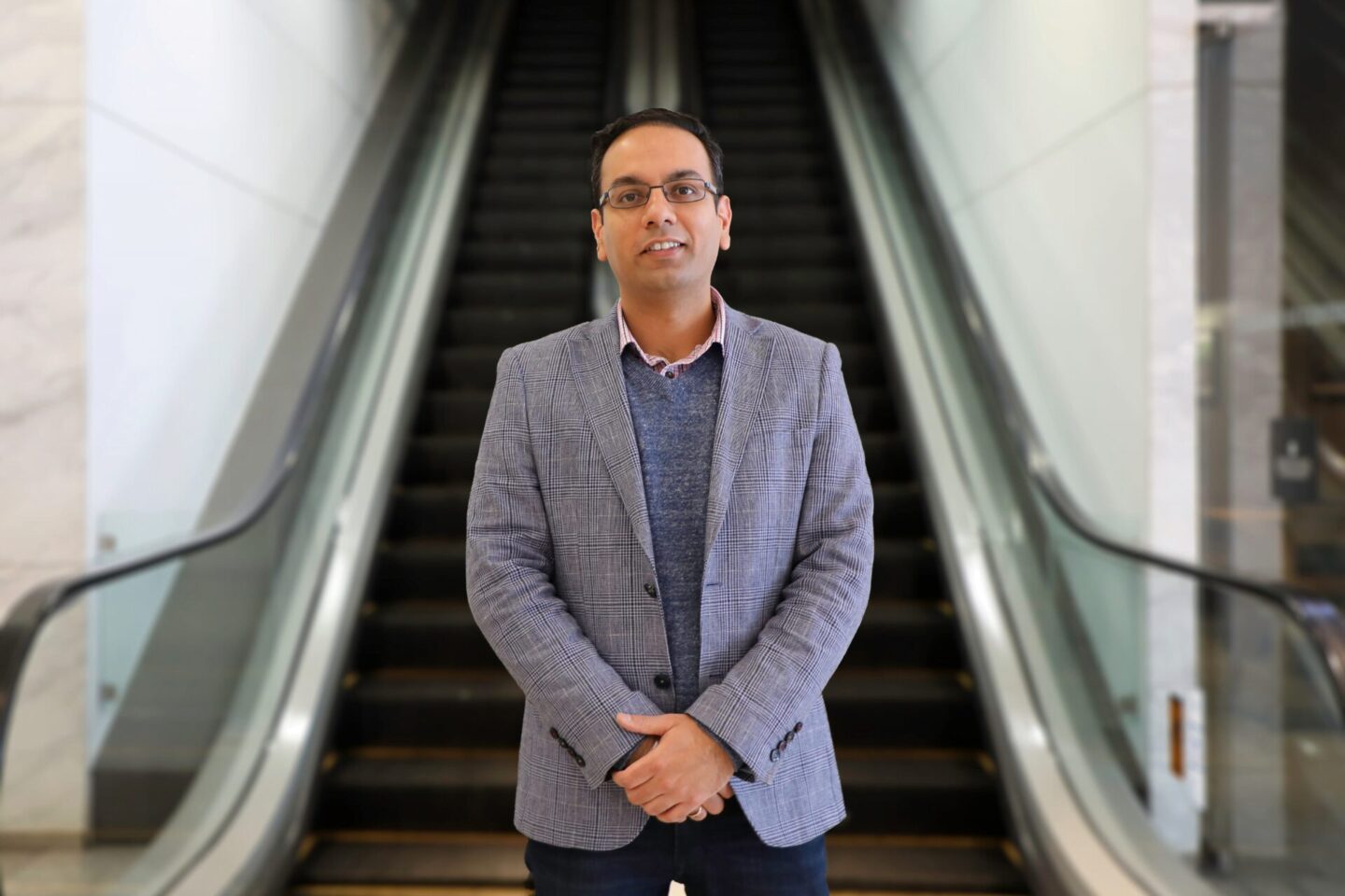 Mandeep Sodhi standing in front of an escalator