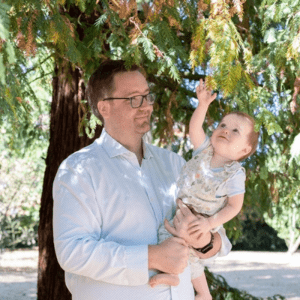Elliott under a tree holding his baby son.