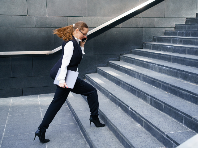female founder / business woman walking up stairs, talking on her phone